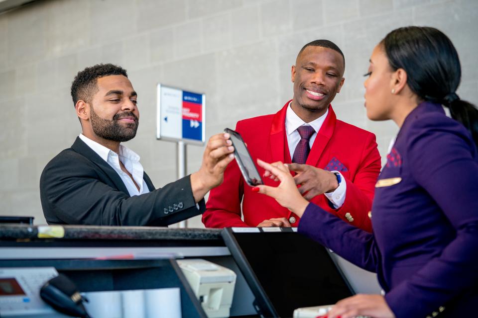Delta customer service agents help a customer with a mobile boarding pass.