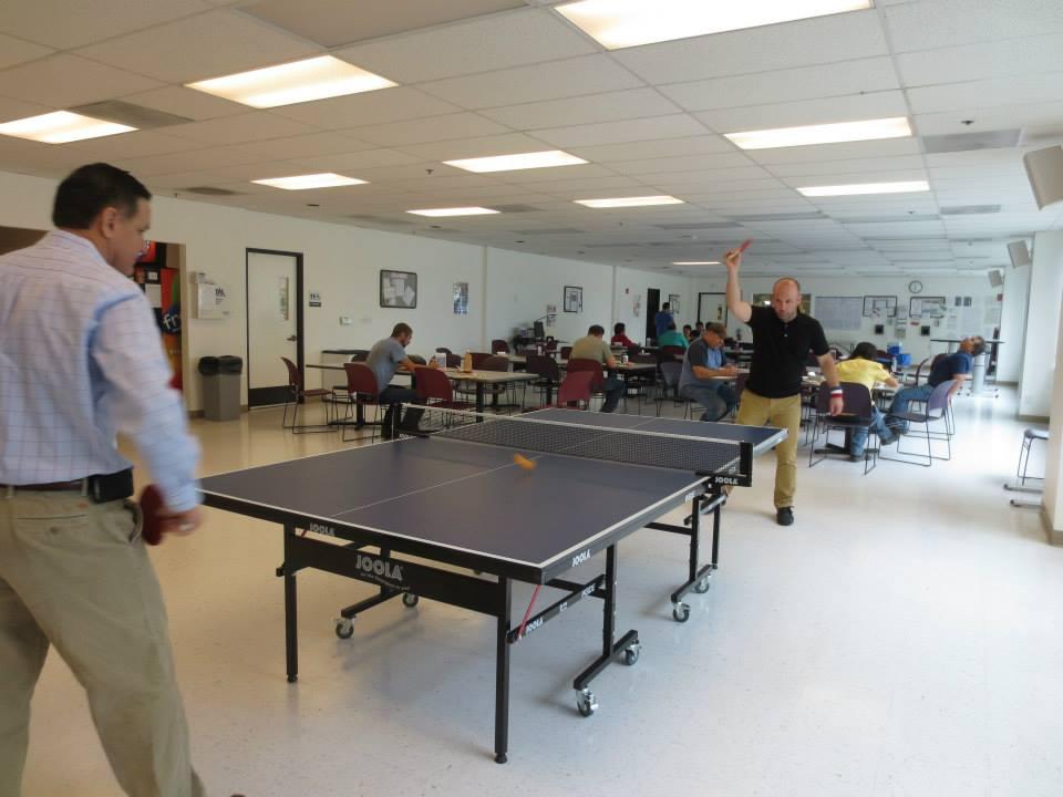 Workrite employees using the ping pong table in the employee breakroom.