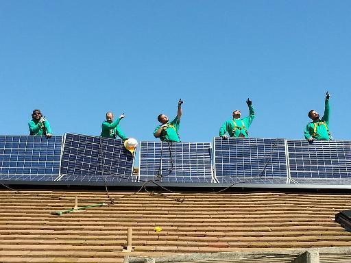 SolarCity installers pose on a roof.
