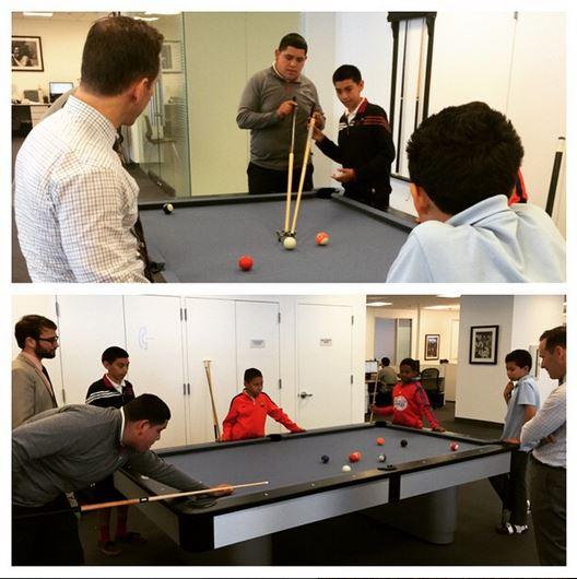 Employees playing pool with their mentees during an office visit as part of our foundation's mentor program.