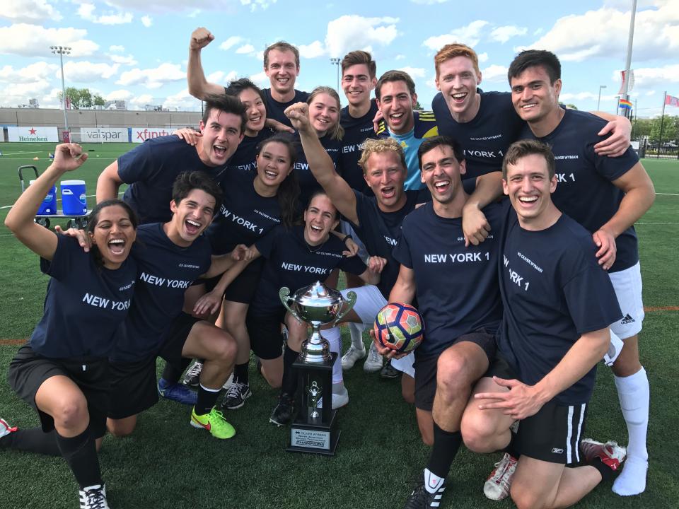 Oliver Wyman North American Soccer Tournament winners posing with their trophy and celebrating their victorious win!