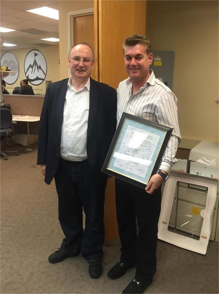 Stavros Papastavrou, the founder and an owner of The Money Source, celebrating 18 years of business with an employee.