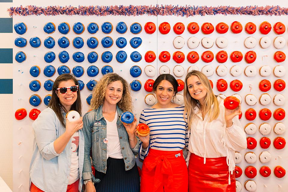 Employees pose in front of a larger than life donut wall at our quarterly Thirsty Thursday.